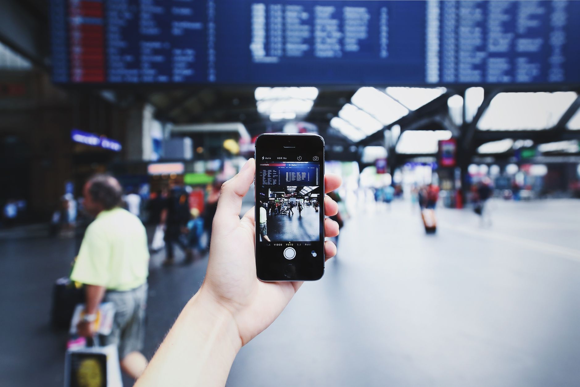 Reisender mit einem Smartphone in einem Bahnhof