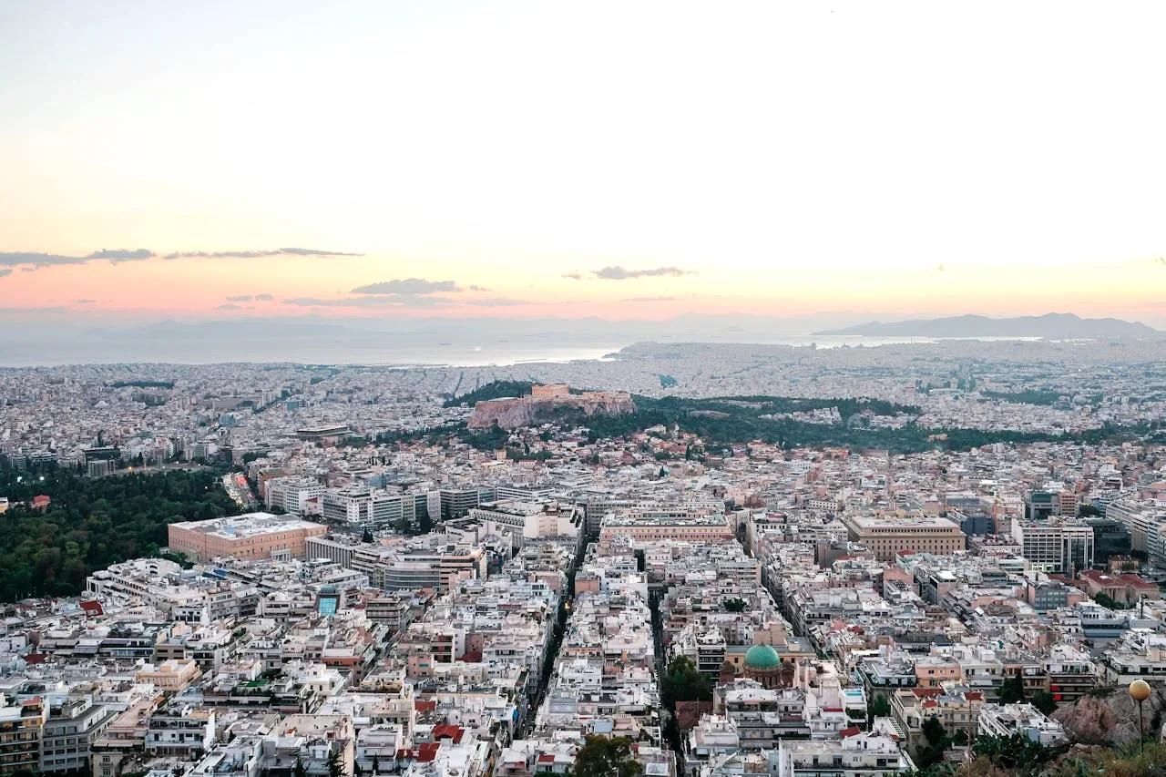 Skyline van Athene bij zonsondergang met de Akropolis in de verte