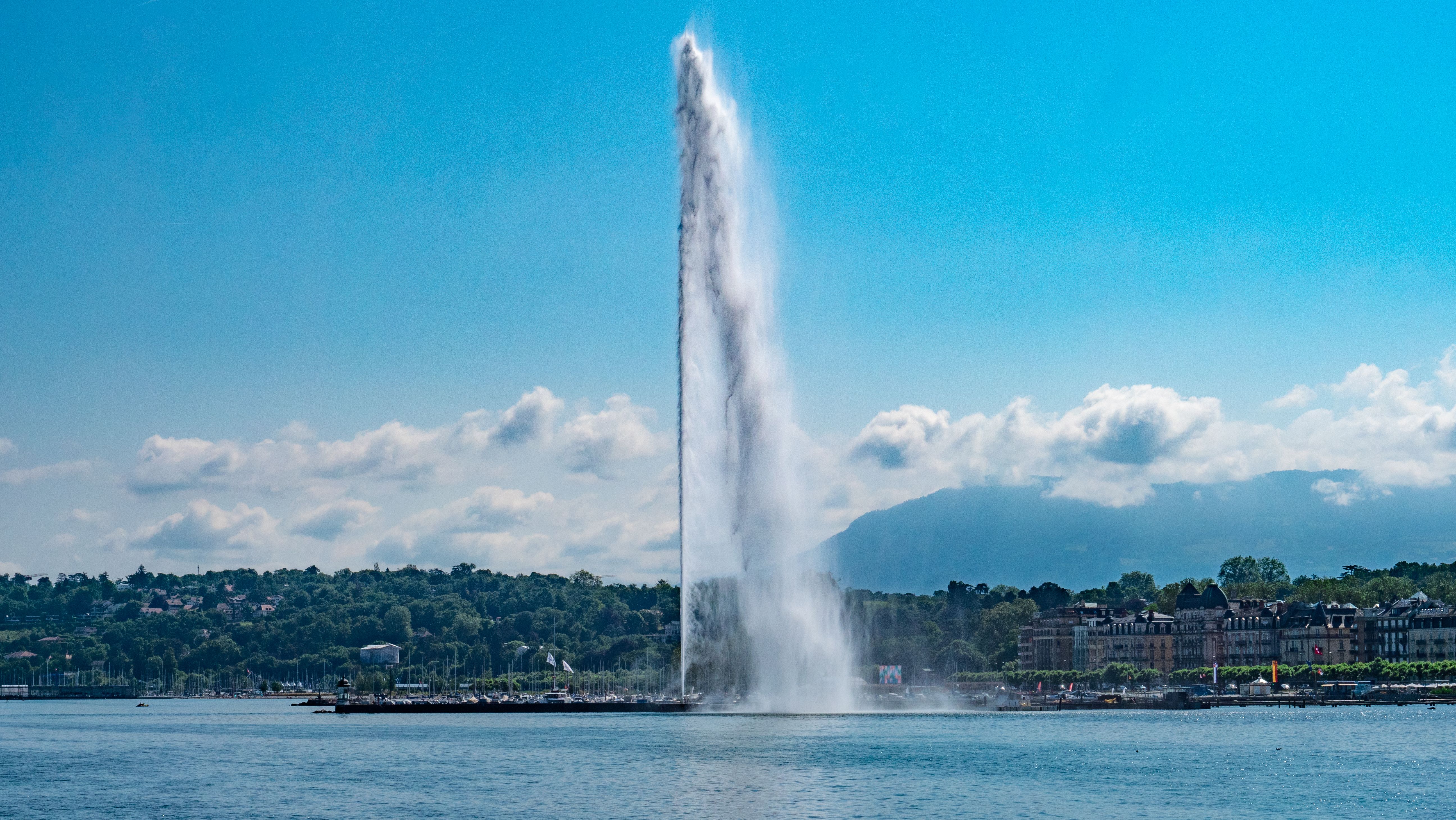 De Jet d'Eau van Genève spuit uit het meer onder een blauwe lucht