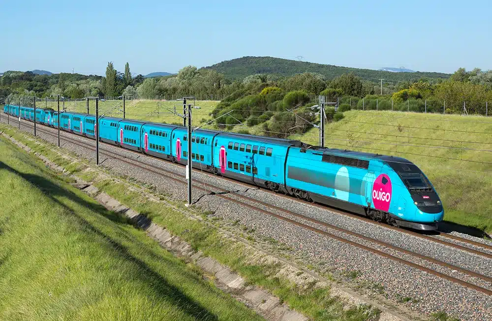 Blue Ouigo train traveling through countryside