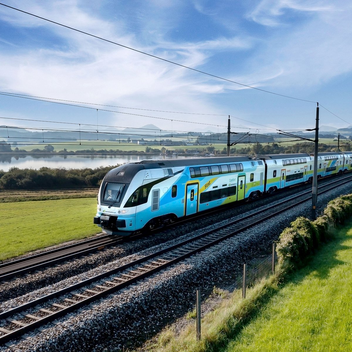 Blue and white WESTbahn train on railway tracks