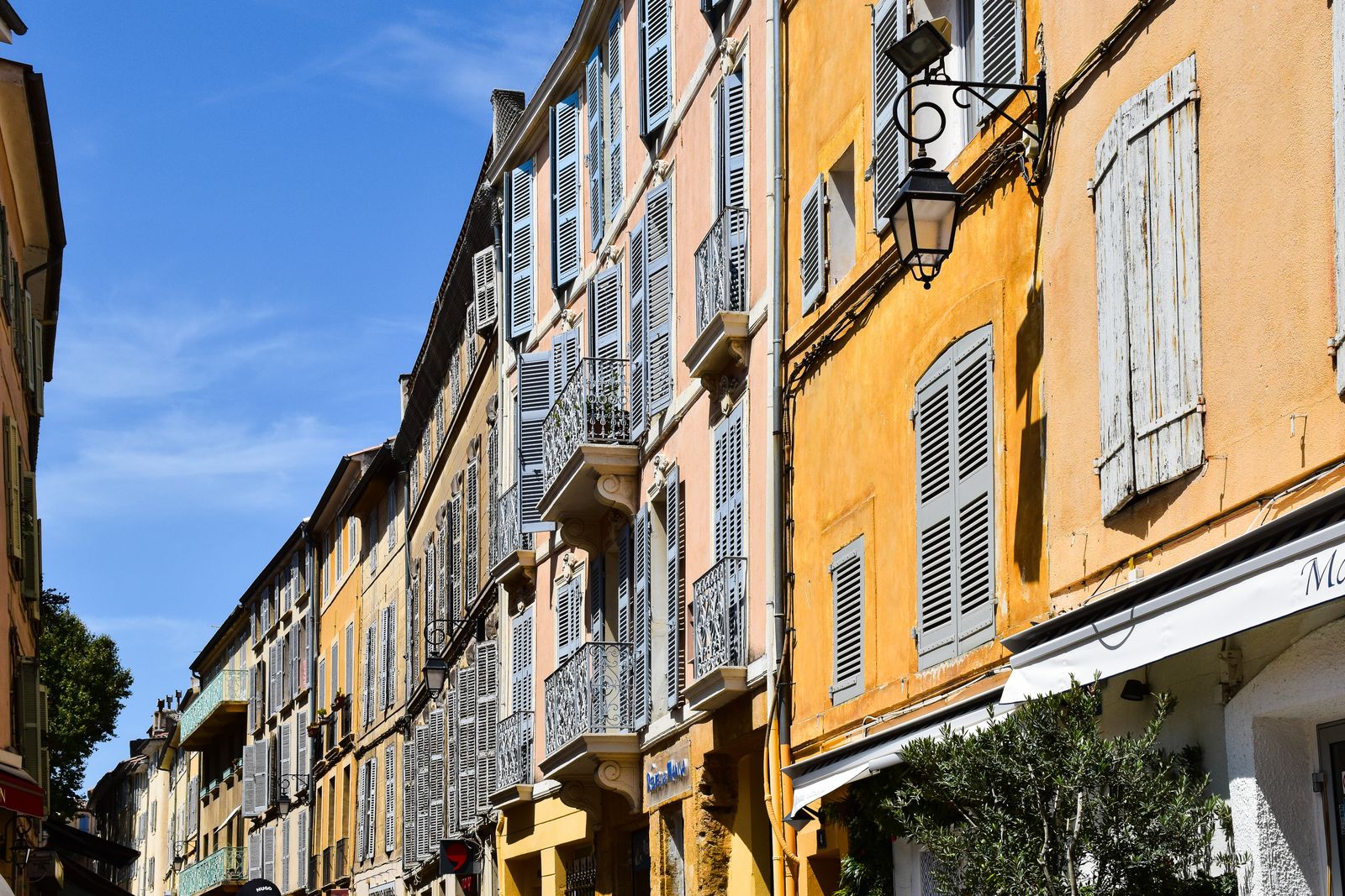 Historic ochre facades and shuttered windows on a sunny street in Aix-en-Provence.