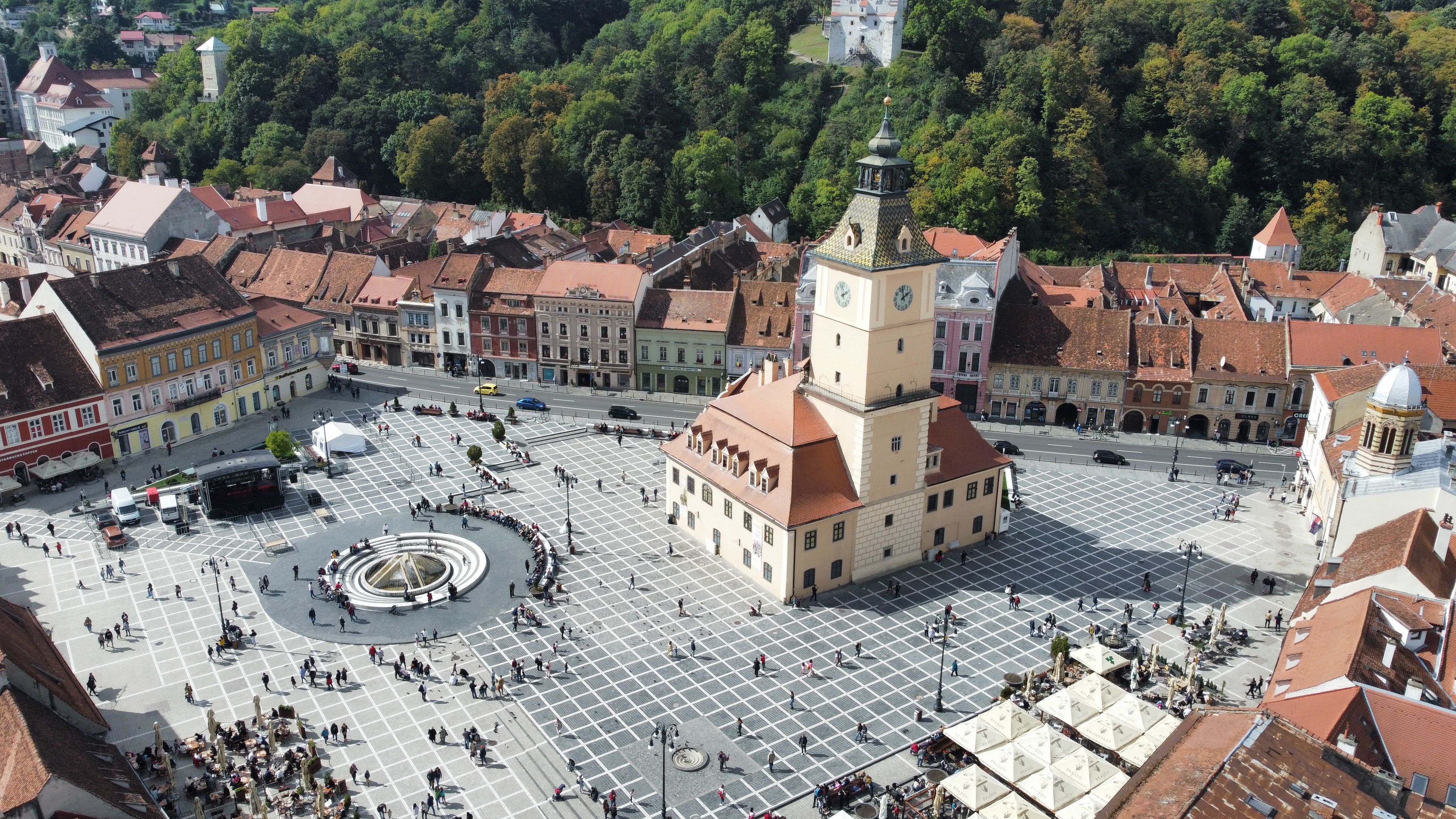Piața Sfatului in Brașov seen from above, with the Council House clock tower and the wooded Tâmpa hill behind