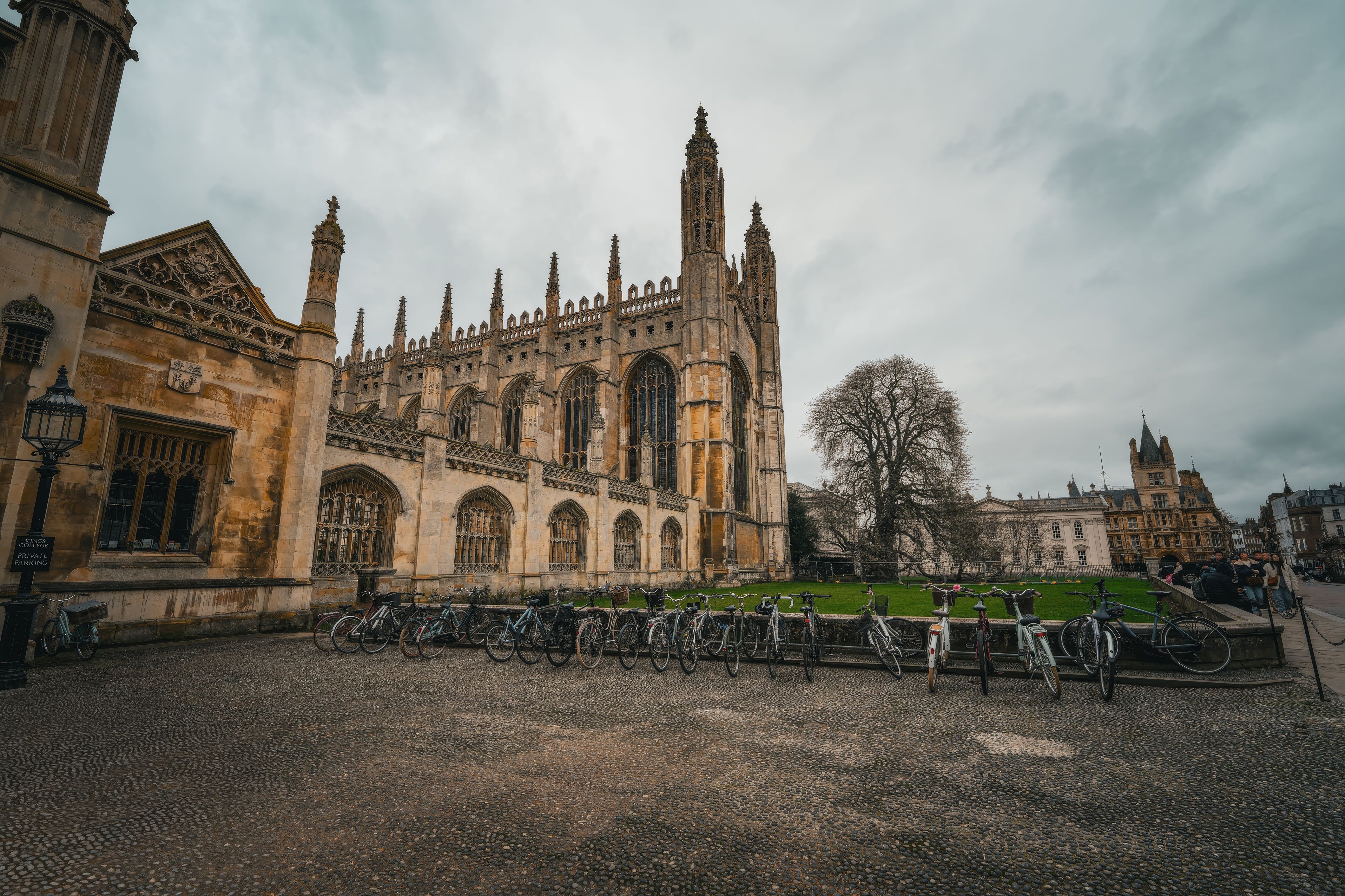 King's College Chapel in Cambridge, with bicycles parked along the lawn in front under a cloudy sky
