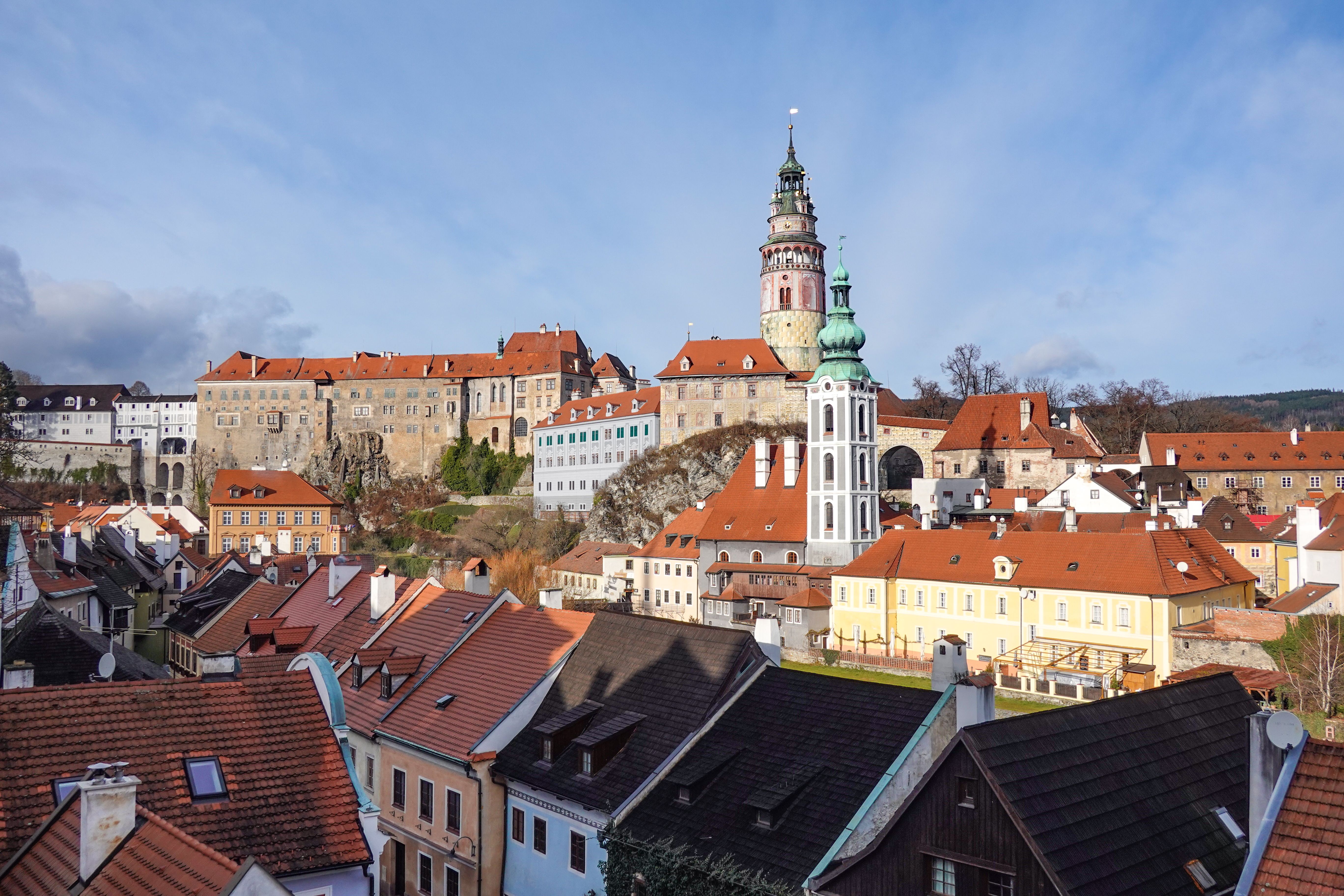 La torre del castillo de Český Krumlov sobre los tejados rojos del casco antiguo bajo un cielo azul