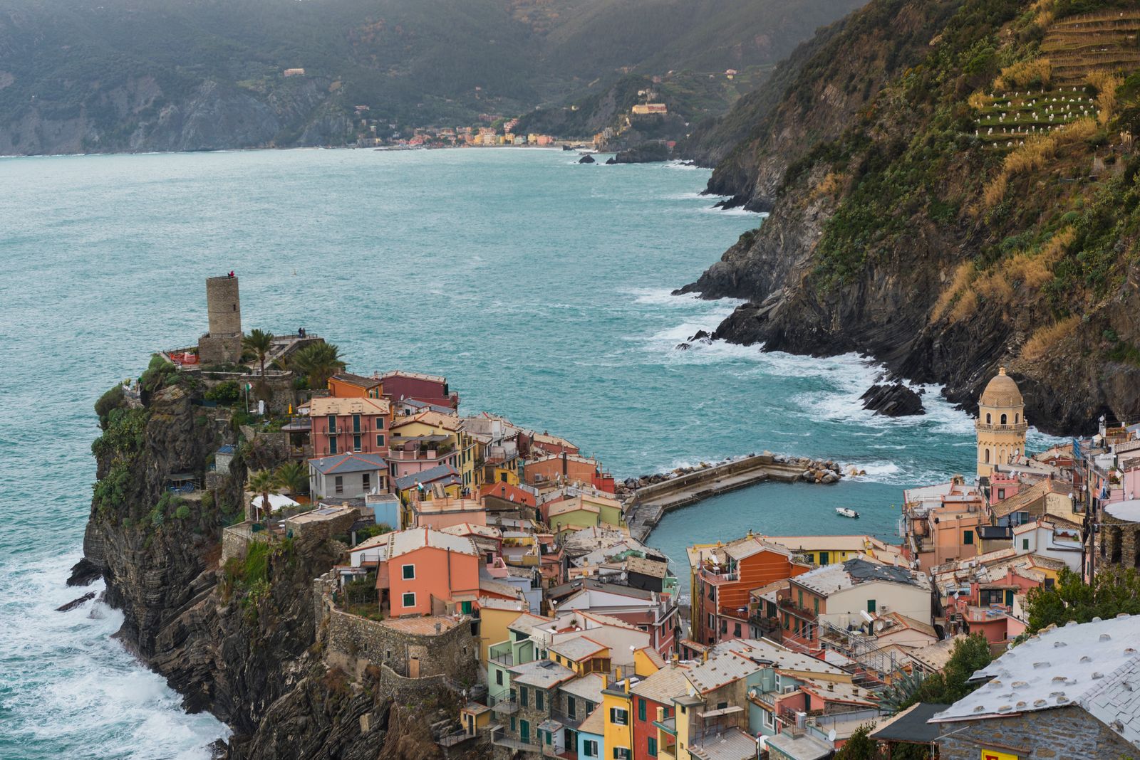 De kleurrijke haven van Vernazza en de huizen langs de kliffen aan de kust van Cinque Terre.