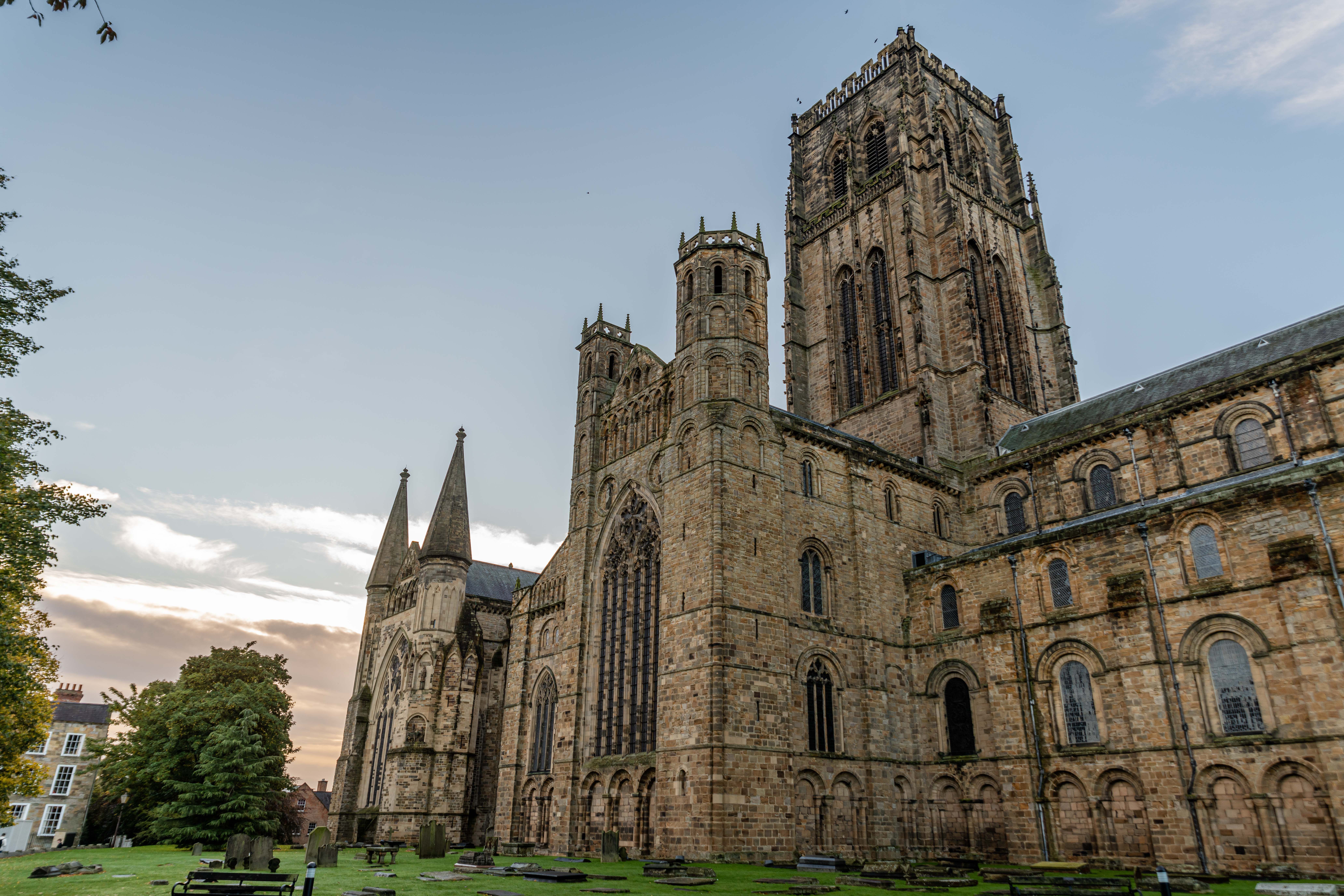 Durham Cathedral and its central tower rising above lawns at dusk