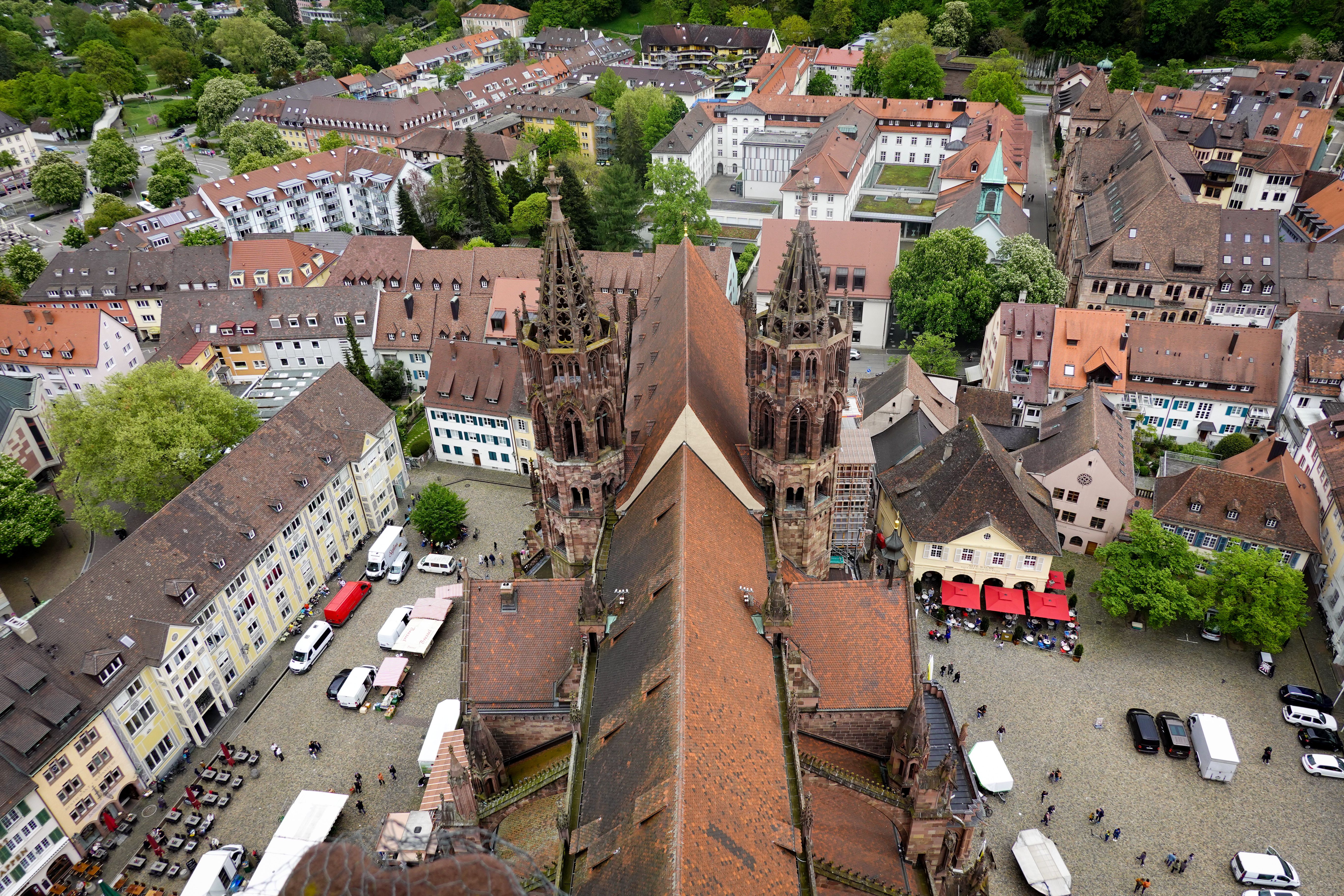 Veduta aerea delle guglie del duomo di Friburgo sopra Münsterplatz e le bancarelle del mercato nella città vecchia
