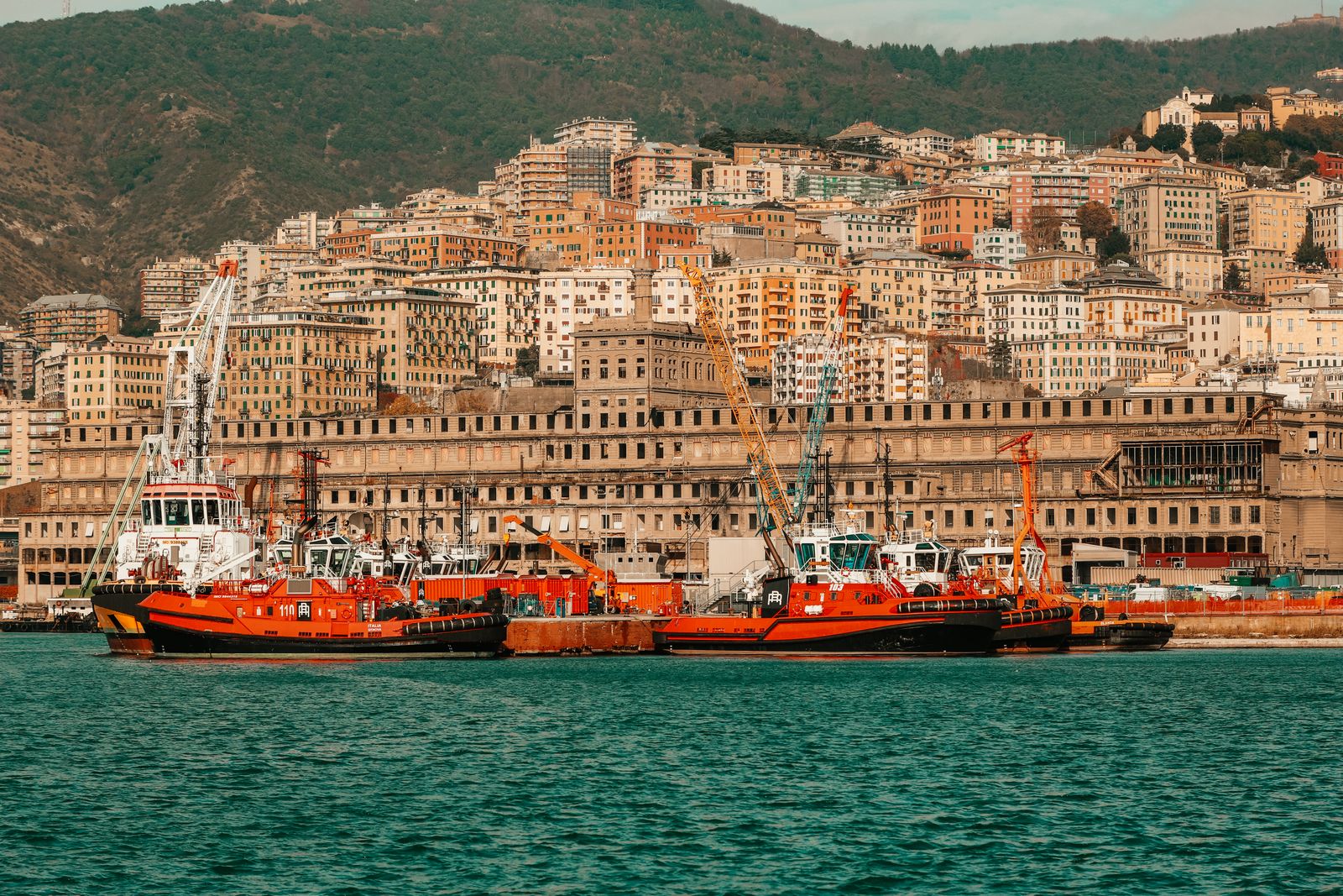 Genoa's harbour with working boats and the hillside city behind it.