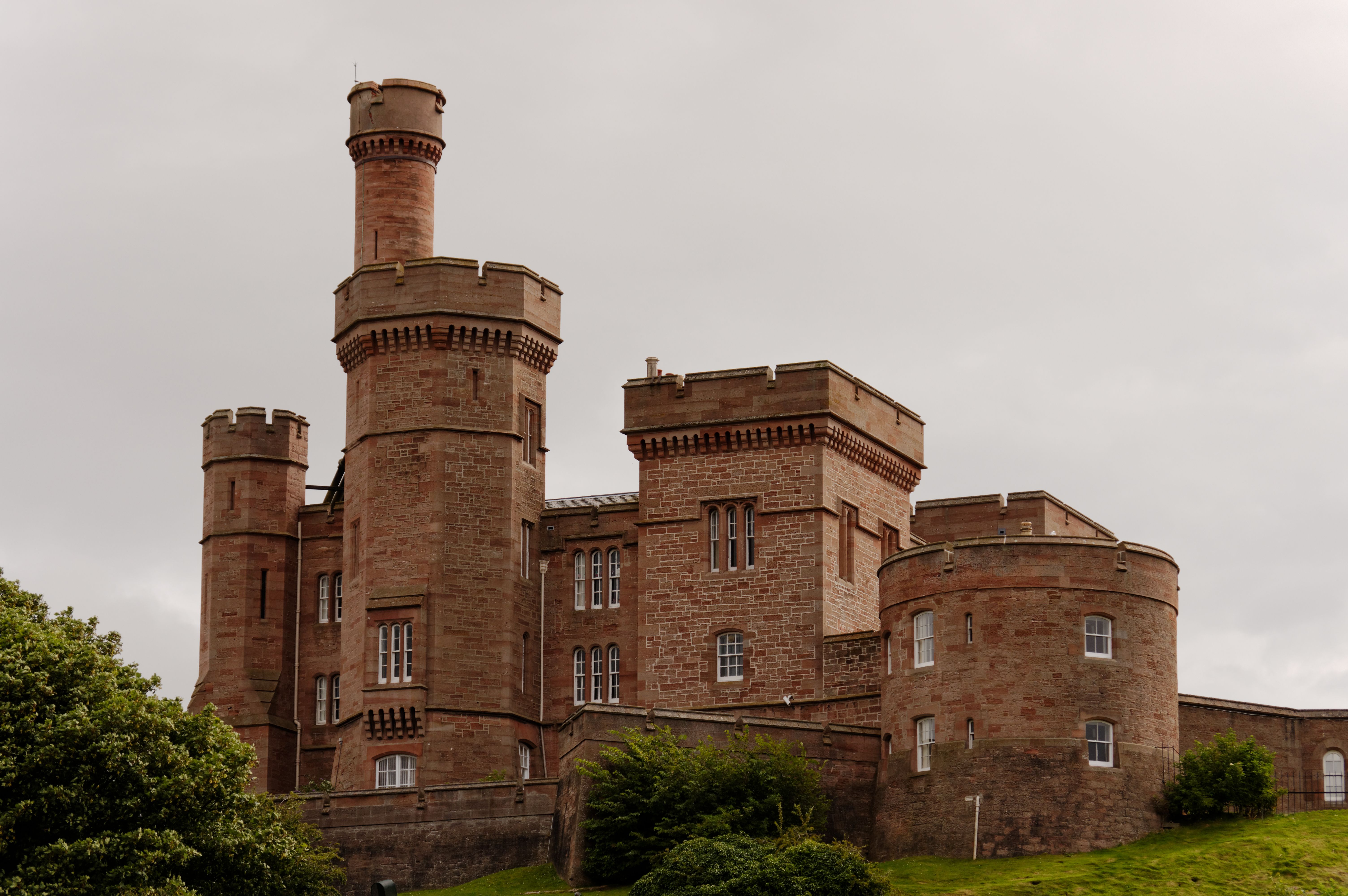 Red sandstone towers of Inverness Castle on its hill, seen from the grass slope below