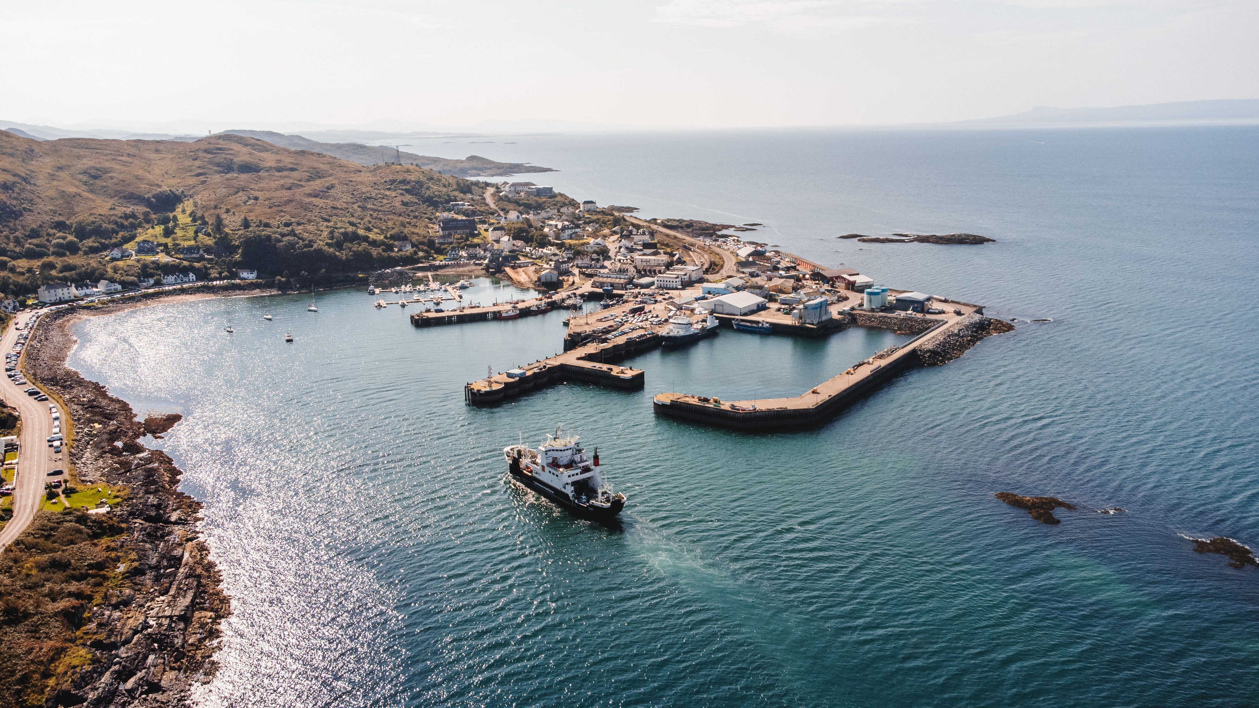 Aerial view of Mallaig harbour with a ferry arriving, the village and hills beyond