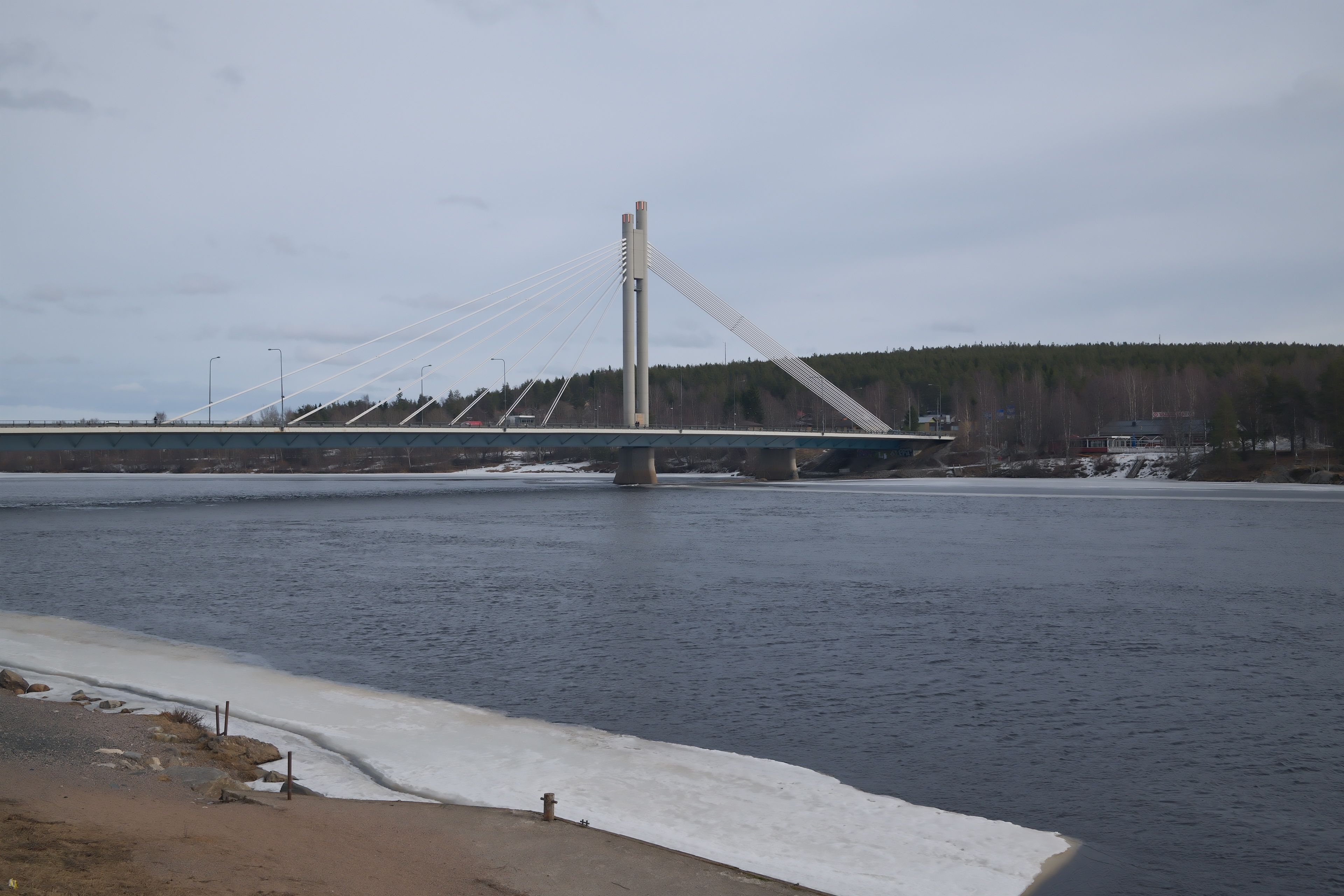 Schrägseilbrücke Jätkänkynttilä über den Fluss Kemijoki in Rovaniemi, Finnland, mit Eis am Ufer im Spätwinter
