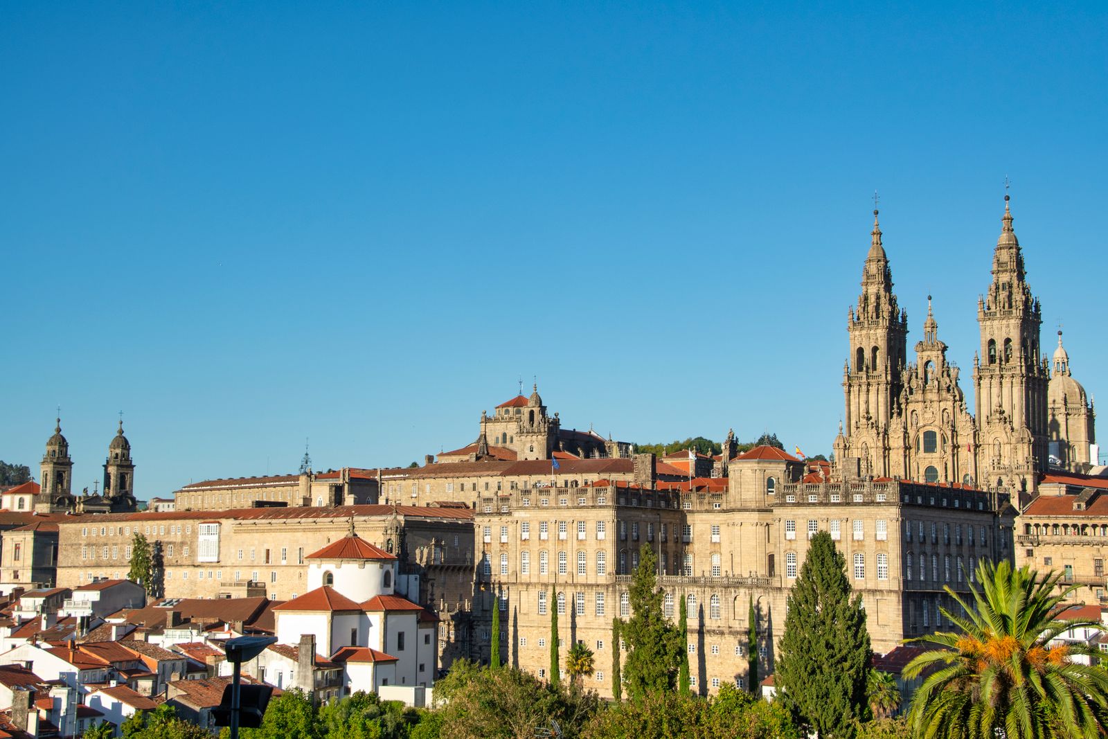 Santiago de Compostela Cathedral and historic rooftops under a clear blue sky.