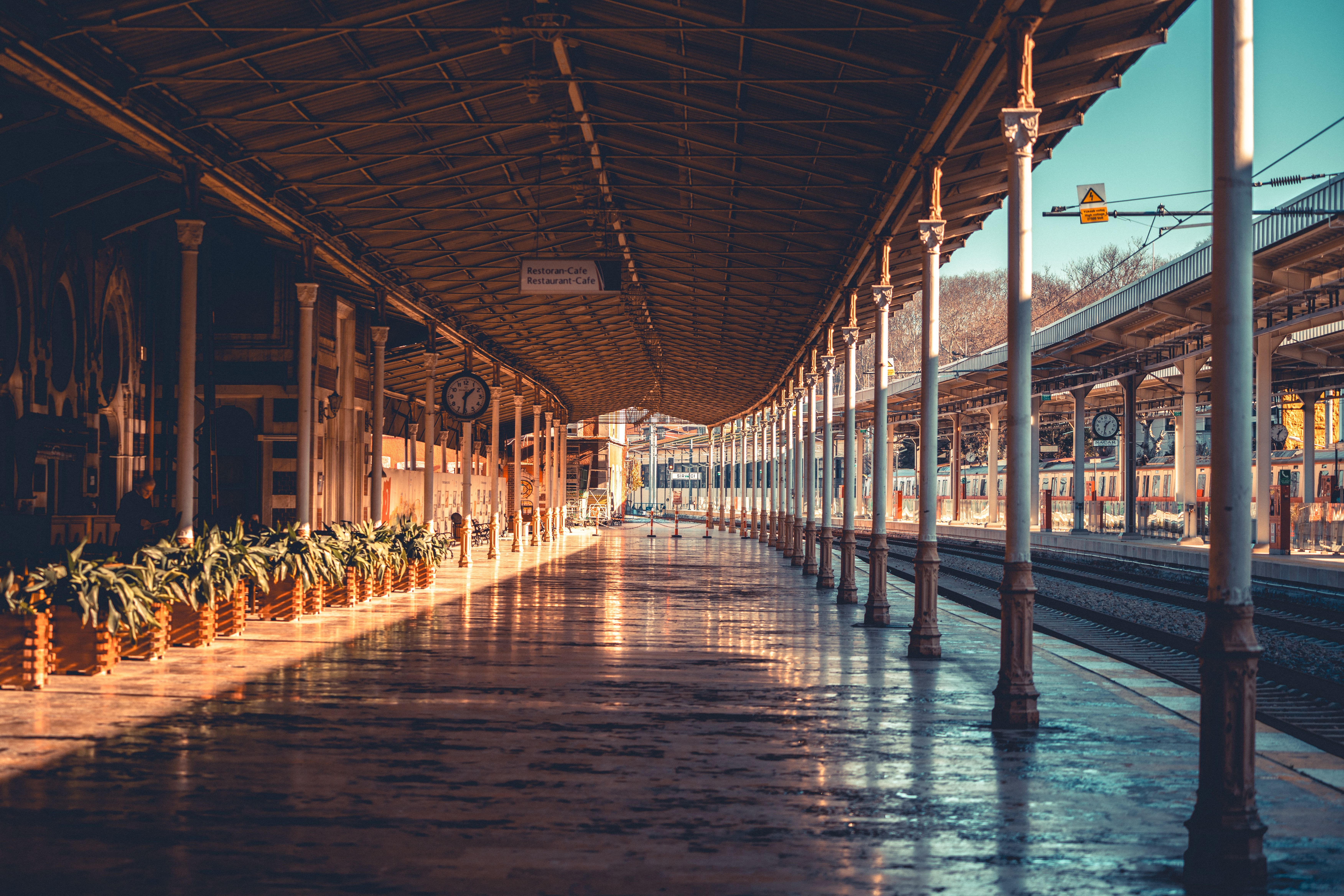 Antico binario deserto della stazione ferroviaria di Sirkeci a Istanbul, con pensilina in ferro battuto, colonne e rotaie illuminate dalla calda luce pomeridiana.