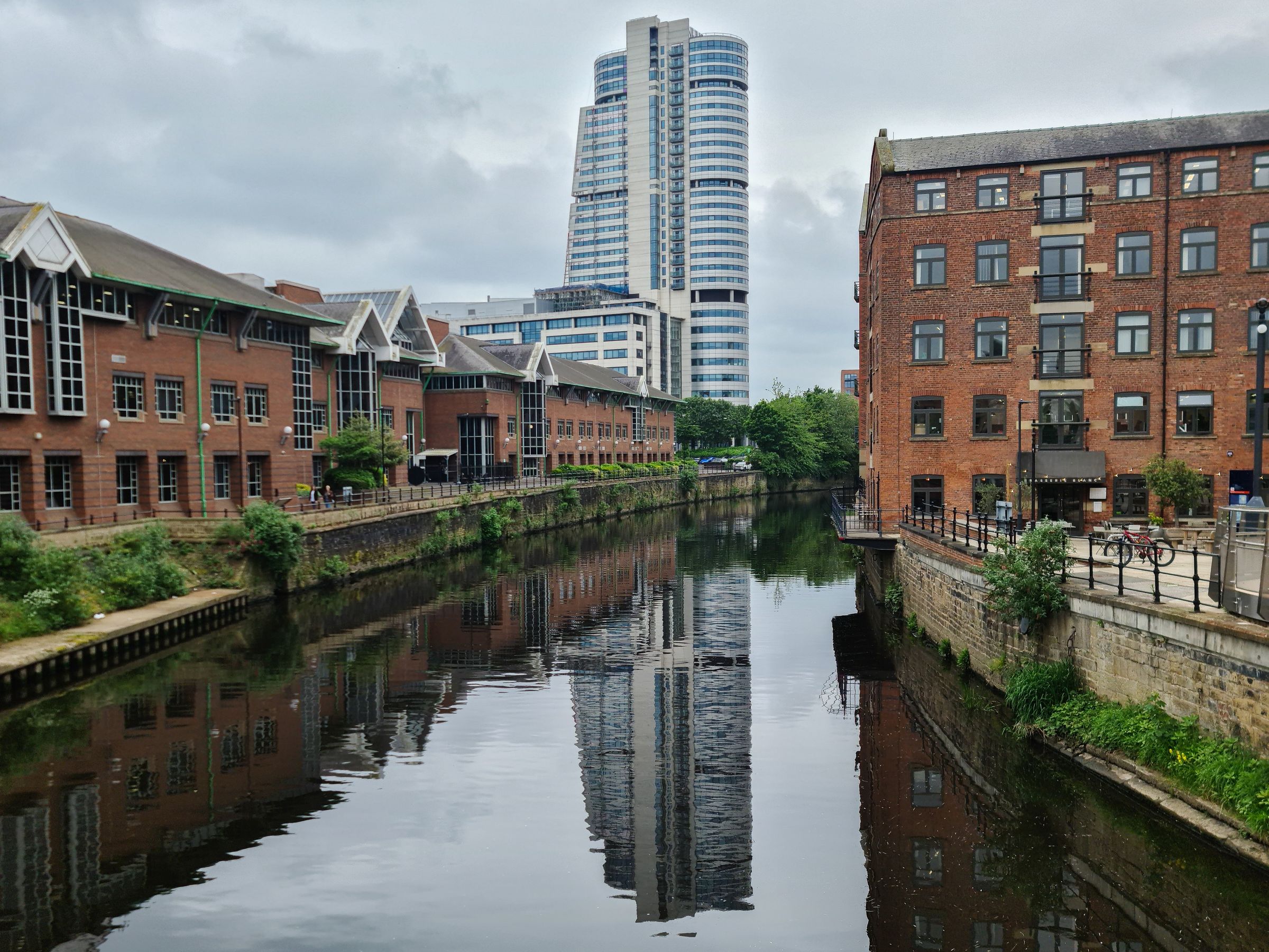 Brick buildings and the Bridgewater Place tower reflected in the water in central Leeds
